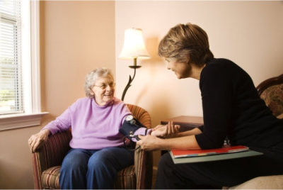 nurse checks on an elderly woman's blood pressure
